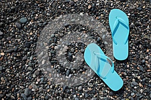 Stylish turquoise flip lops on pebble beach, flat lay. Space for text