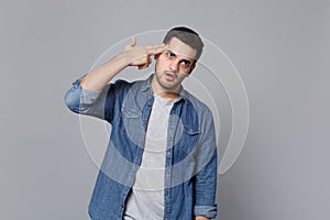 Stylish unshaven young man in denim jeans shirt posing isolated on grey wall background studio portrait. People