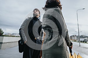 Stylish urban couple walking together on an overcast day with yellow umbrella.