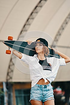 Stylish urban girl posing with Longboard