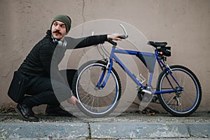 Stylish urban man with a bicycle resting against a wall