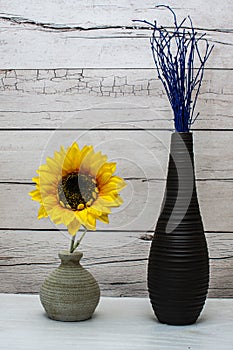 Stylish vases with fake sunflower and blue twigs