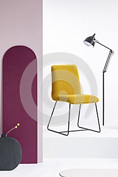 Stylish velvet yellow chair next to tall industrial black lamp in white interior