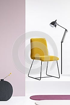 Stylish velvet yellow chair next to tall industrial black lamp in white interior