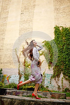 Stylish and very beautiful brunette girl in gray suit jumping up