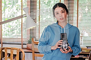 Stylish vintage female photographer holding her old  twin lens camera to her chest as she composes her image photo