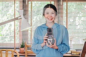 Stylish vintage female photographer holding her old  twin lens camera to her chest as she composes her image