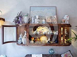 Stylish vintage interior. Close-up of retro wooden shelf on wall. Lots of porcelain and decorative figurines.