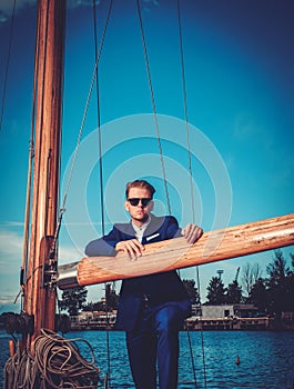 Stylish wealthy man on a luxury wooden regatta