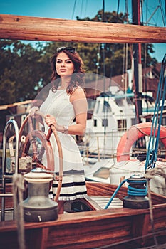 Stylish wealthy woman on a luxury wooden regatta