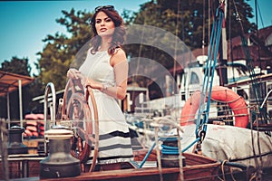 Stylish wealthy woman on a luxury wooden regatta