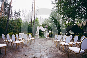 Stylish wedding arch for the newlyweds and chairs for the guests of the ceremony, in the park