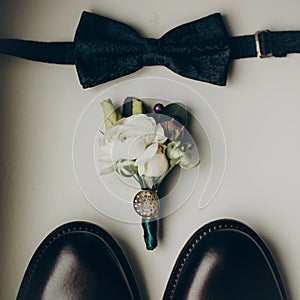 Stylish wedding bow tie with modern flowers bouquet and shoes on wooden background top view. rustic wedding morning preparation.