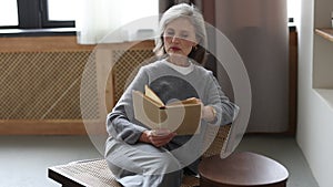 stylish well-groomed caucasian Middle aged older woman in a cozy home environment reading a book a love story while