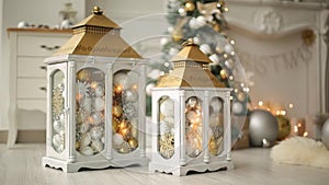 Stylish white christmas interior with decorated lanterns, fireplace, lanterns, lamps, candles, bumps. Comfort home with