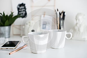 Stylish white desktop, home office interior details with two cof