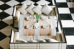 Stylish white dining table and sofas. Minimalist interior in monochrome. Black and white concept. Empty restaurant top