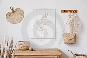 Stylish white interior of living room with mock up poster frame, rattan decoration, leaf, wooden shelf, dried flowers. photo