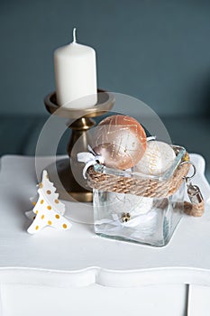 Stylish white large candl on the table, and New Year`s balls, photos in gentle pastel colors. Christmas mood