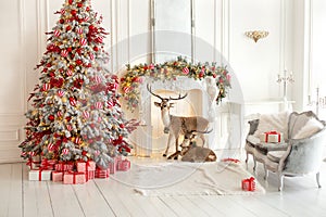 Stylish white living room interior with decorated Christmas tree, fireplace and sofa with pillows.