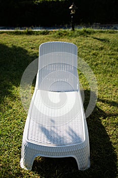 Stylish white lounger made of plastic on the lawn.