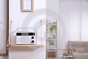 Stylish white radio on wooden shelf indoors, space for text