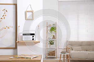 Stylish white radio on wooden shelf in living room interior