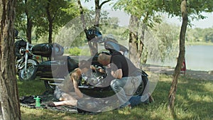 Stylish woman biker repairing motorcycle in park