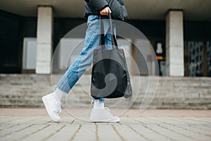 Stylish woman in bloodstains and jeans with a bag in hand, close photo of legs