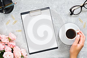 Stylish woman desk with blank paper clipboard mockup, pink rose flowers, gift box with gold color ribbon, coffee cup, glasses on