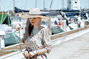 Stylish woman in floral dress with sunglasses on pier