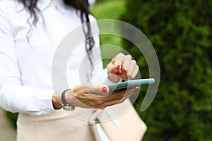 Stylish woman holds a smartphone in her hands and points to screen with her finger