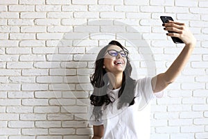 Stylish woman making selfie with shopping bag on the yellow wall background. Winter holiday sale