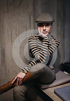 Stylish woman in newsboy hat posing indoors