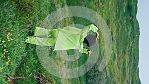 Stylish woman performer dancing walking on green field cloudy evening vertically