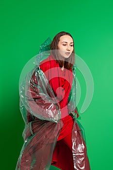 Stylish woman in plastic raincoat in studio