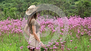 stylish woman in safari clothes stands in the savanna among purple flowers