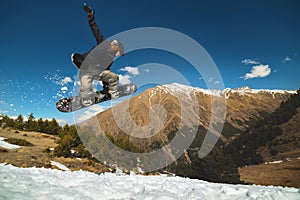 Stylish woman snowboarder makes a trick in flight. Snowboard jump from a kicker against the backdrop of mountains