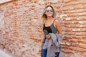 Stylish woman standing near brick wall in city