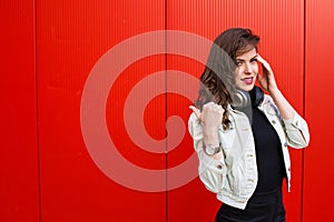 Stylish woman standing near red wall