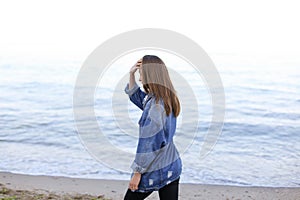 Stylish woman steps confidently along seashore and poses in came