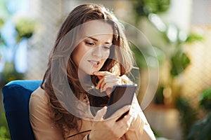 Stylish woman in sunny day sending text message using phone