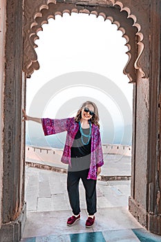 Stylish Woman tourist poses in an arched doorway of the Monsoon Palace in Udaipur India