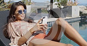 Stylish woman using smartphone at poolside