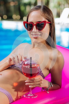 Stylish woman wearing bright red sunglasses lying on air mattress