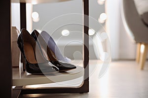 Stylish women`s shoes on rack in modern boutique. Space for text