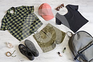 Stylish women`s or teenager`s clothing set with accessories: checkered shirt, black jersey top, green jeans shorts, pink cap,