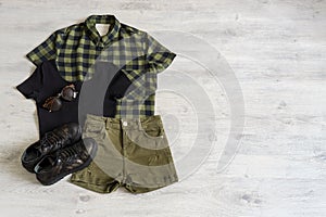 Stylish women`s or teenager`s clothing set with accessories: checkered shirt, black jersey top, green jeans shorts, sunglasses a