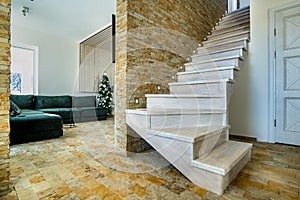 Stylish wooden contemporary staircase inside loft house interior. Modern hallway with decorative limestone brick walls and white