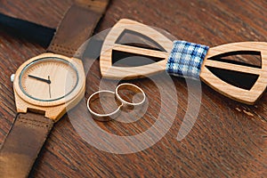 Stylish wooden watch and bow tie for groom on a table in hotel room. Morning preparation before wedding ceremony. Men accessory